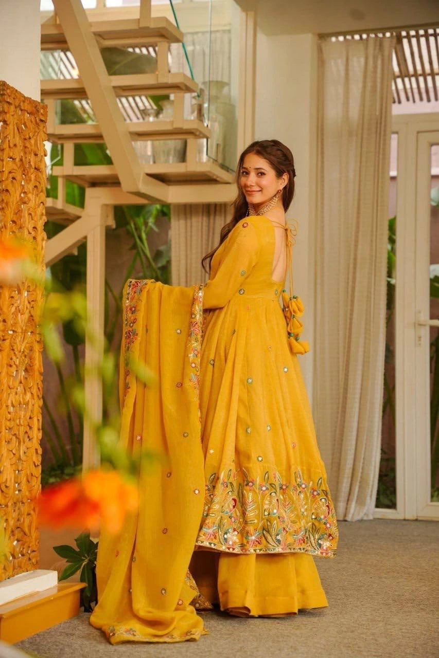 Woman in a yellow saree with floral patterns indoors